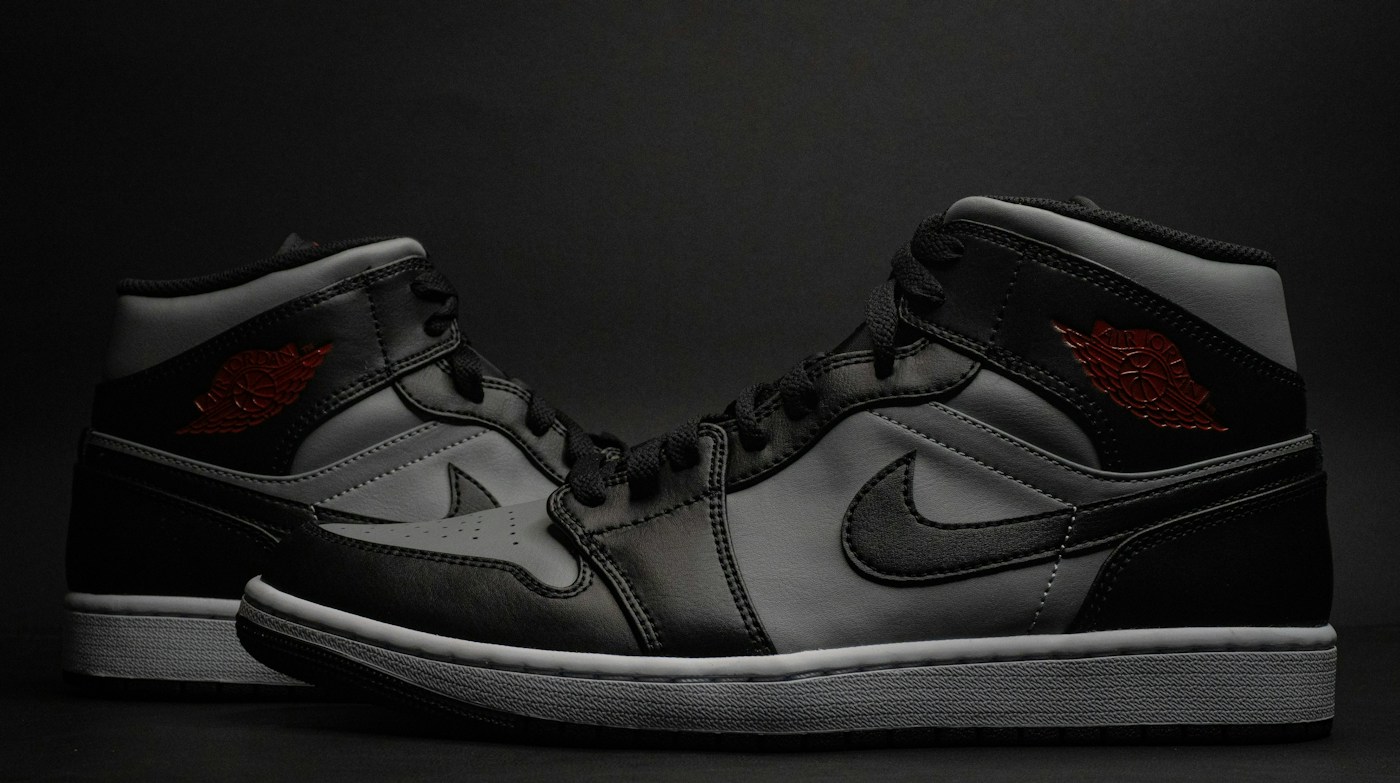 Black and grey sports sneakers with red accents against a dark background